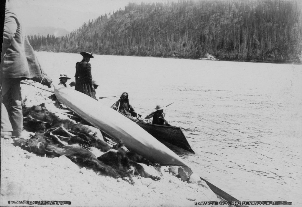 A rare image of Sinixt people around 1900, on the shores of Lower Arrow Lake with traditional sturgeon-nosed canoes.  